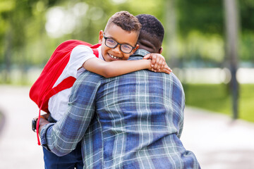 joyful ethnic boy hugging dad after school lessons.