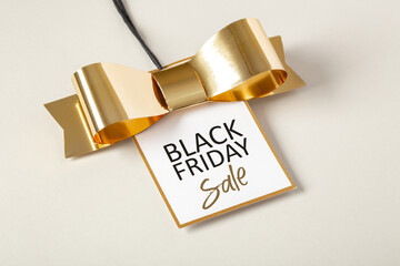 Black friday sale tag with gold border and bow on beige background