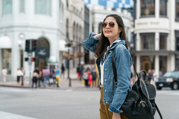 Fototapeta premium chinese woman standing on street is combing hair with hand and looking back with a charming smile.