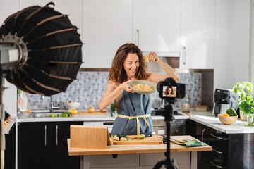 mature woman cooks at home making videos for social media, digital content creator, blogger.