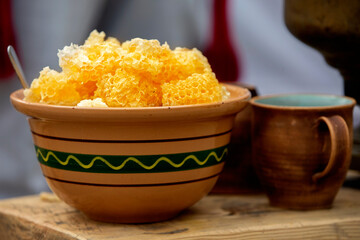 Honeycombs with honey in a clay bowl on a rustic table.