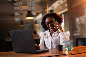 Black businesswoman working on laptop. Portrait of beautiful businesswoman in the office. Woman taking to the phone..