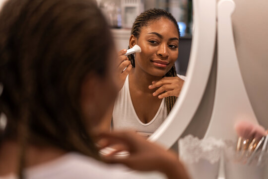 Smiling of african american woman clean healthy skin looking at mirror.beauty and fashion,hair,black skin,skin care,cosmetics,cosmetology,african girl apply cream moisturizer on face.spa and wellness