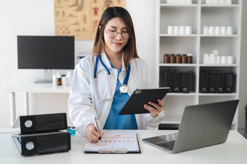 Female doctor working on desk with tablet, laptop computer and paperwork in the office. Medical and doctor concept.