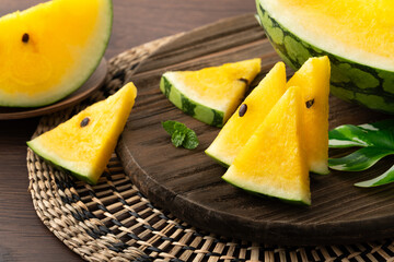 Sliced yellow watermelon in a plate on wooden table background.