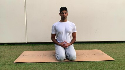 Hombre indio practicando técnicas de respiración. Sesión de meditación sobre colchoneta de yoga en el parque. Relax al aire libre para una mejor salud. Ejercicios de concentración por la mañana en ver