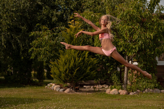 A little girl is professionally engaged in gymnastics and shows her skills in the summer on the street