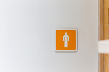Orange male or man toilet sign on the wall. copy space background