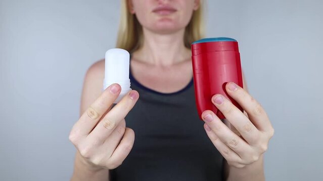 left or right. Girl chooses between eco-friendly deodorant without toxins and antiperspirant with toxic elements. In left hand Mineral alum crystal stick, in right hand classic remedy chemical nature