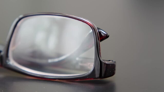 Front view of reading glasses with brown frames on a black office table. Close-up of  spectacles.