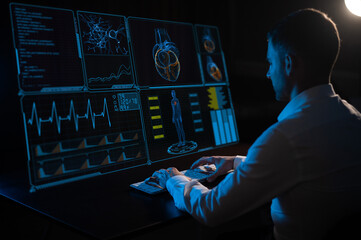 A caucasian man sits in the dark in front of a virtual menu and types on a keyboard. Readings on the life support monitor. 