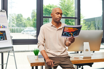 inclusion, myasthenia gravis, bold african american businessman standing with walking cane and looking at charts near computer monitor, dark skinned office worker in casual attire