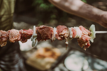 Man stringing pieces of fresh meat on steel skewer