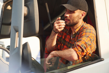 Talking by using radio. Young truck driver in casual clothes