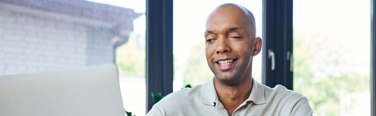 Naklejka premium chronic illness, positive african american businessman with eye syndrome looking at laptop, myasthenia gravis, bold and dark skinned office worker, inclusion, diversity in society, banner