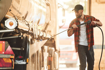 Process of washing the vehicle. Young truck driver in casual clothes