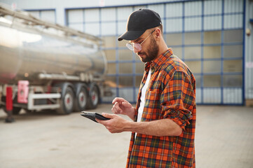 Holding tablet. Young truck driver in casual clothes