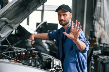 Fototapeta na wymiar No trespassing, don't disturb hand gesture. Auto mechanic working in garage. Repair service