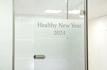 New year greeting. Text Sign  - Healthy New Year 2024. Waiting Room. Glass door in a doctor's...