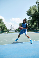 Young man, athlete in blue uniform training, playing basketball outdoors on warm summer day....