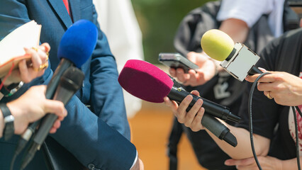 Media coverage as journalists with microphones gather at a press conference, delivering informative insights and capturing the essence of the event  - obrazy, fototapety, plakaty