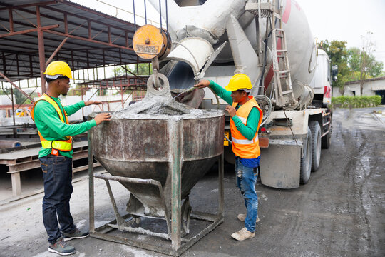 Mason construction worker working on site with Civil Engineer. Asian builders working pouring concrete in mold from mixer concrete truck. Manufacturing Prefabricated concrete walls factory