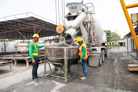 Mason construction worker working on site with Civil Engineer. Asian builders working pouring concrete in mold from mixer concrete truck. Manufacturing Prefabricated concrete walls factory