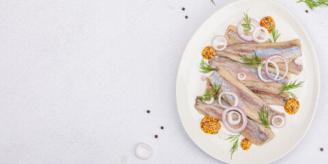 Fototapeta na wymiar Salted herring with dijon mustard, dill and red onion rings. Marinated filleted fish on light stone