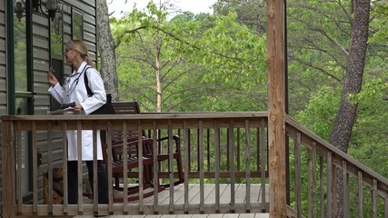 Medium view of mature woman doctor or nurse making a house call home visit in a rural area.
