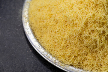 Preparing kadayif for kadayif dessert on a traditional metal plate, wire kadayif, top view