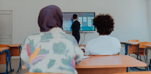 A diverse group of students is attentively listening, actively participating, and embracing modern education in a dynamic classroom setting, fostering collaboration and stimulating creativity.