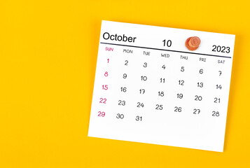 The October 2023 and wooden push pin on yellow background.