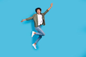 Obraz premium Full length portrait of overjoyed cheerful man jumping empty space isolated on blue color background