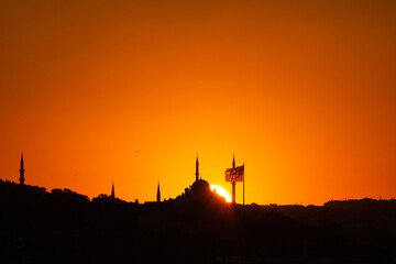 Istanbul silhouette at sunset. Mosque and minarets with flag.