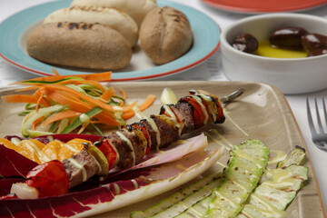 Greek souvlaki skewers served on the plate with vegetables in the restaurant	
