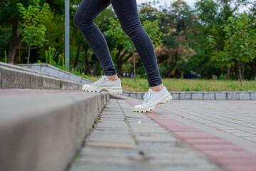 White sneakers with studded soles on female legs in black jeans