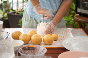 Female baker pressing raw dough bun with mold to make beautiful mooncake. Mooncake making process