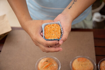 Female Hand showing square mooncake into the camera for demonstrating 