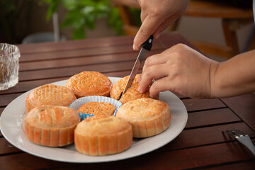 Photo of female hand using knife to cut a mooncake by half