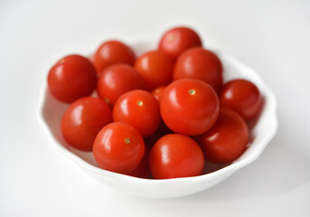 Red fruits of small tomatoes in a glass plate. Juicy cherry tomatoes.