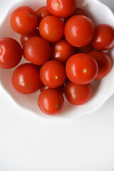 Red fruits of small tomatoes in a glass plate. Juicy cherry tomatoes.