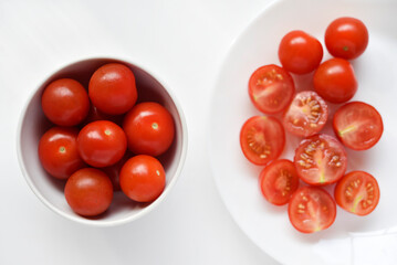 Fresh red fruits of small tomatoes on a glass plate. Juicy chopped cherry tomatoes.