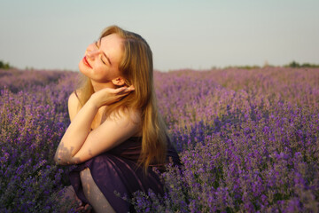 beautiful blonde girl with long hair on a lavender field in the evening - 625567785