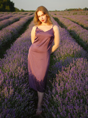 beautiful blonde girl with long hair on a lavender field in the evening - 625567953