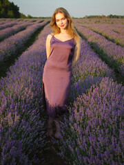 beautiful blonde girl with long hair on a lavender field in the evening - 625568121