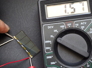 Tiny solar cell voltage test with multimeter. Focused on cell.