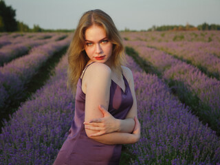 beautiful blonde girl with long hair on a lavender field in the evening - 625568586