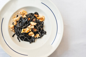 Overhead view on serving portion of Italian squid ink pasta with shrimps served in white plate