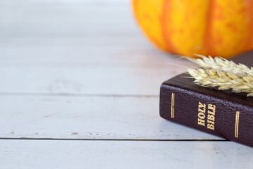 Holy bible book, ripe ears of wheat, and pumpkin on wooden table. Closeup, copy space. Christian...