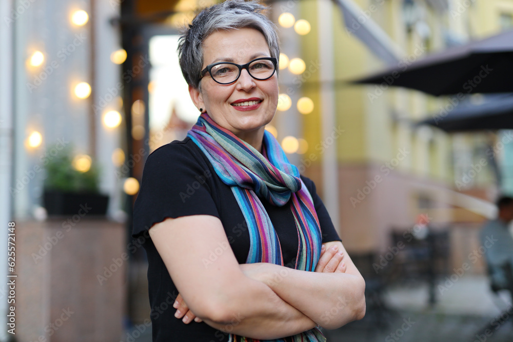 Poster Portrait of a mature confident woman in glasses with her arms crossed.